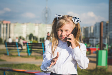 Little girl on the street talking on the phone and writing a message