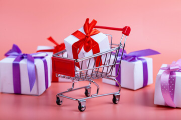 Shopping cart and gifts on a pink background.