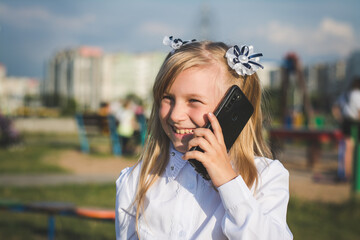 Little girl on the street talking on the phone and writing a message