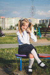 Little girl on the street talking on the phone and writing a message