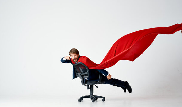 a man in a suit with a red cloak rides in a superman chair