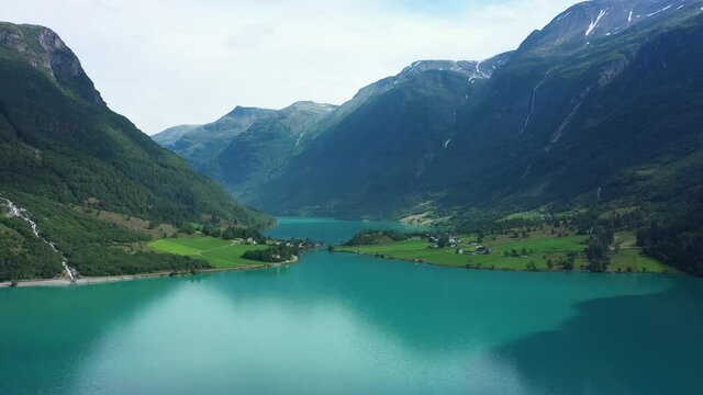 Spectacular Oldedalen valley and Oldevatnet freshwater lake - Turqoise glacial water and tall mountains with lush mountainside - Summer day panoramic aerial