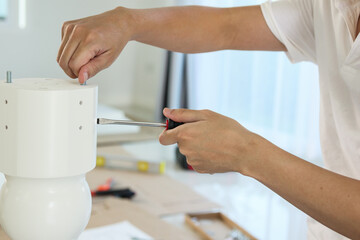 Asian man assembling white table furniture at home