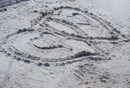 On the sand there is an image of two hearts.