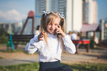 Little girl on the street talking on the phone and writing a message