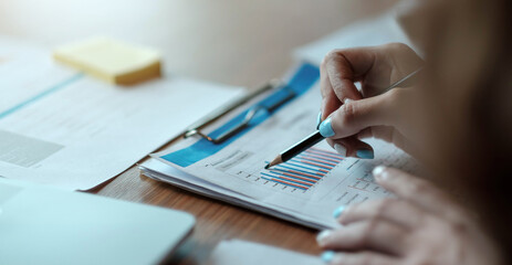 Business people hold a pen to point to charts, graphs, finance, and analyze and calculate business success planning processes planning strategies.