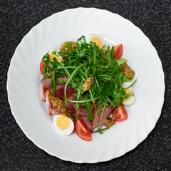 Delicious salad with medium beef, fresh vegetables, arugula and eggs. Top view