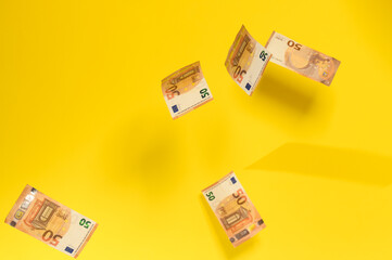 Rain of euro bills, flying falling money on a yellow background, European currency in the face of fifty euros.