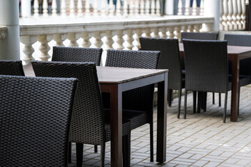 Tables made of wood stove and woven wire chairs of black color stand at the granite railings.