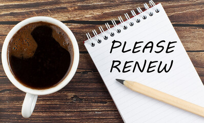 PLEASE RENEW text on notebook with coffee on wooden background