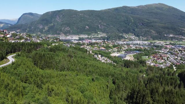 Sideways moving aerial of F&oslash;rde and F&oslash;rdefjorden sea from a distance - Watching road and forest with panoramic city overview