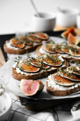 toast with figs, cream cheese and thyme on a black plate on the breakfast table, healthy vegetarian snack or dish, white background, close up, flat lay