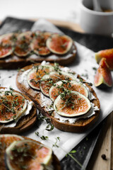 toast with figs, cream cheese and thyme on a black plate on the breakfast table, healthy vegetarian snack or dish, white background, close up, flat lay