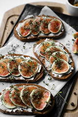toast with figs, cream cheese and thyme on a black plate on the breakfast table, healthy vegetarian snack or dish, white background, close up, flat lay
