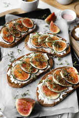 toast with figs, cream cheese and thyme on a black plate on the breakfast table, healthy vegetarian snack or dish, white background, close up, flat lay