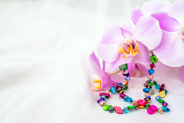 Fototapeta na wymiar Bracelet on white fabric and purple Orchid 