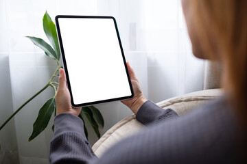 Mockup image of a woman holding digital tablet with blank white desktop screen at home