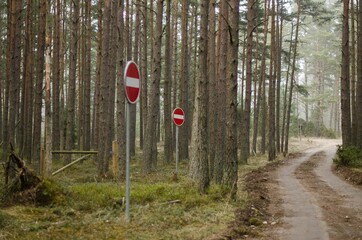 Forest road with several no entry signs and a barrier.