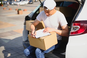 Young Delivery Man Checking List On Clipboard In car