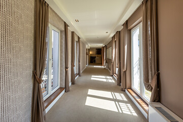 Interior of a carpeted hotel corridor with windows