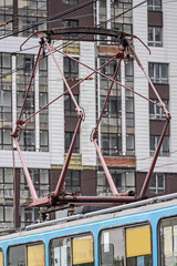 Tram pantograph on the background of a multi-storey building on a summer day