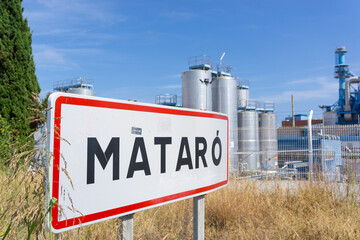 Image of the traffic sign of the entrance of the city of MATARO with the factories next to it