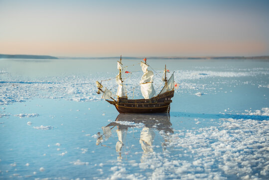 Model Of A Sailboat In The Water Of A Salt Lake And A Beautiful Sunset Landscape.