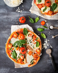 Italian cuisine. Pizza with tomatoes, spinach and mozzarella. Vegetarian pizza without meat. Italian food on a dark background. A cut slice of pizza margherita