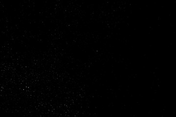 Falling snow on a black background. small particles with bright dots starry sky. Сhaotic white bokeh. light spots texture. abstract.