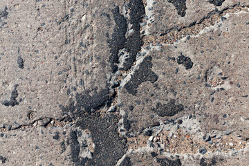 a bad asphalt road that has been repaired many times