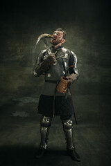 Portrait of one brutal bearded man, medeival warrior or knight over dark background.