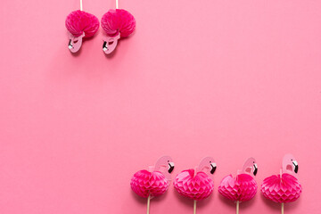 pink party toothpicks in a shape of flamingo on a pink background. origami 