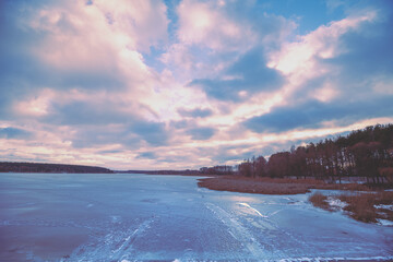 Dramatic winter sunset over the frozen lake. Serene lake in the evening. Nature landscape