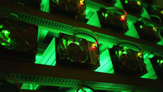 Bitcoin miners in large farm. ASIC mining equipment on stand racks mine cryptocurrency in steel container. Blockchain techology application specific integrated circuit rig. Server room lights.