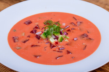 Cold beetroot soup with vegetables on wooden table
