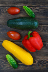 Zucchini, cucumber, tomato and pepper, a background of colorful summer vegetables on a wooden table, a ripe harvest of red and yellow colors, ingredients for making a salad