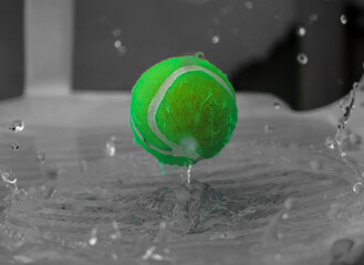 Slow motion capture of tennis ball splashing water.