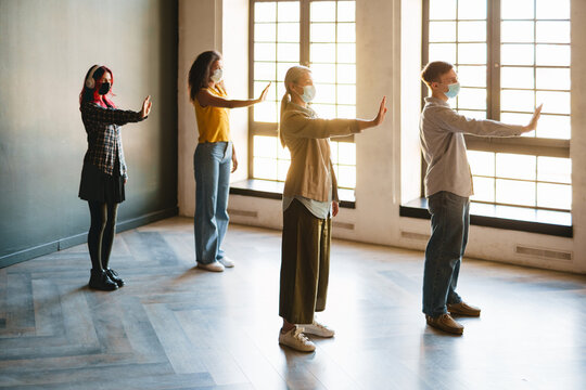 Mature teacher and students in face mask doing exercise in school
