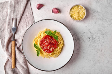 Spaghetti pasta with tomato sauce, parmesan. garlic and basil on white plate with fork and napkin...