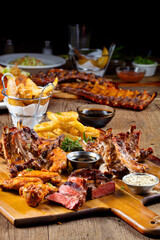 Costillar  de cerdo con salsa barbacoa   On patatas fritas y salsas sobre mesa de madera. Pork Ribs With Barbecue Sauce On French Fries And Sauces On Wooden Table.