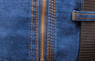 A fragment of blue jeans with a back zip pocket and a black nylon belt