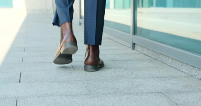 Low section of businessman walking outside office building