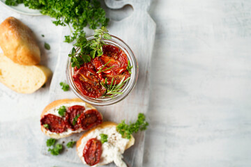 Italian cuisine. Bruschetta with dried tomatoes and cottage cheese. Italian food on a white background. Toasts are being prepared. Dried tomatoes in a jar. Baguette and ricotta