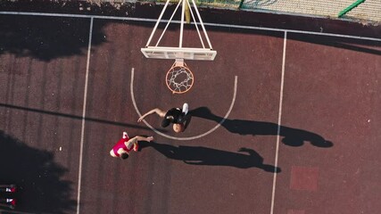 Aero footage of an urban basketball court. The multiracial team is training outdoors. African American athlete makes a hit, double-point shot - Powered by Adobe