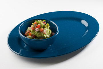 Guacamole en cuenco de porcelana azul sobre fondo blanco. Guacamole in blue porcelain bowl on white background.