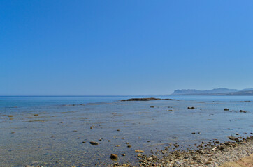 Pebble sea shore and clear blue sky.