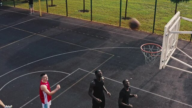 District city multiethnic team has a friendly match meeting with another team. Popular urban sport, basketball game on an city basketball court, top view