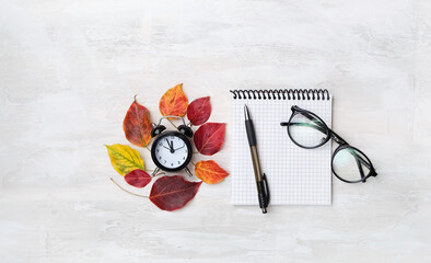 Autumn leaves, empty notebook, pencil, clock alarm, eyeglasses. Autumn time concept. education, starting school, back to school. beginning of school year. flat lay