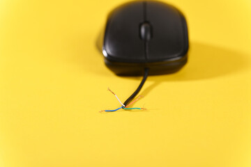 Computer mouse with broken cable on yellow background.