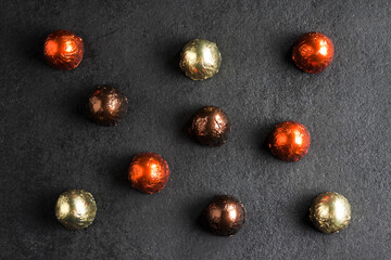 Chocolate candies wrapped in colorful foil on dark background